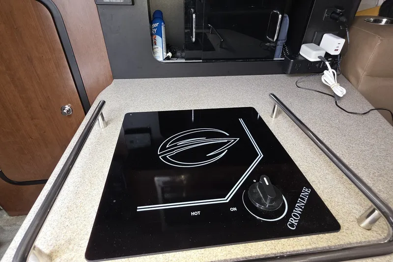 Slide: The Image of Crownline 325 SCR 2017 boat interior with sleek black stovetop on countertop. - 24