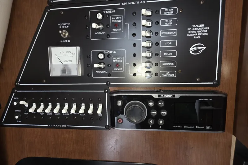 Slide: The Image of Control panel of a 2017 Crownline 325 SCR boat with switches and a Fusion audio system. - 38