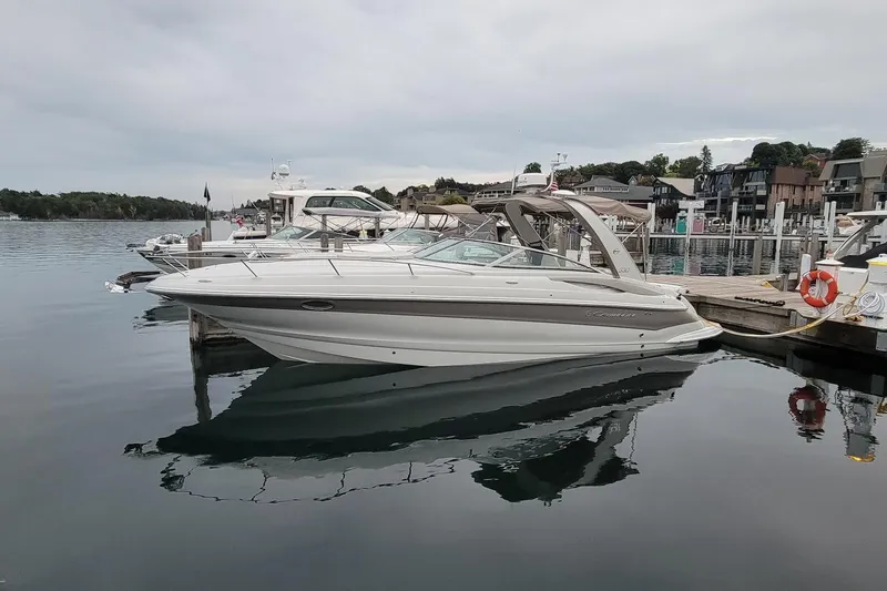 The Image of 2017 Crownline 325 SCR boat docked at a marina, reflecting on calm water. - 0