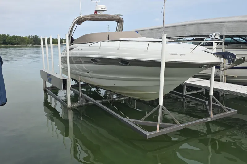 Slide: The Image of 2017 Crownline 325 SCR boat on lift, docked in calm waters. - 2