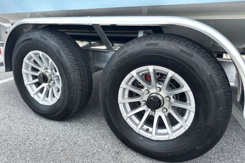 Slide: The Image of Trailer wheels of a 2027 Pathfinder 2400 Tournament boat on pavement. - 23