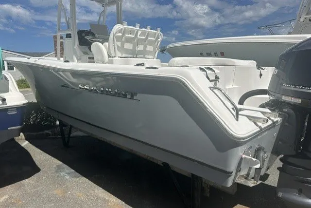 Slide: The Image of 2013 Sea Hunt Ultra 234 boat, white hull, parked outdoors under a cloudy sky. - 1