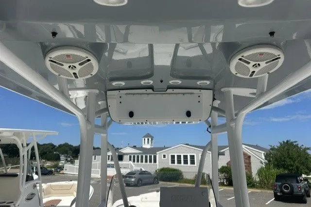 Slide: The Image of 2013 Sea Hunt Ultra 234 boat interior with speakers and console, docked near coastal buildings. - 6