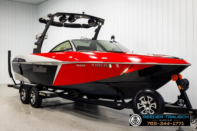 Slide: The Image of 2017 Malibu Wakesetter 25 LSV boat in red and black on trailer indoors. - 2