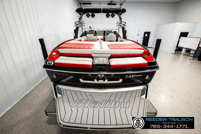 Slide: The Image of 2017 Malibu Wakesetter 25 LSV boat with red and white seating in a showroom. - 54