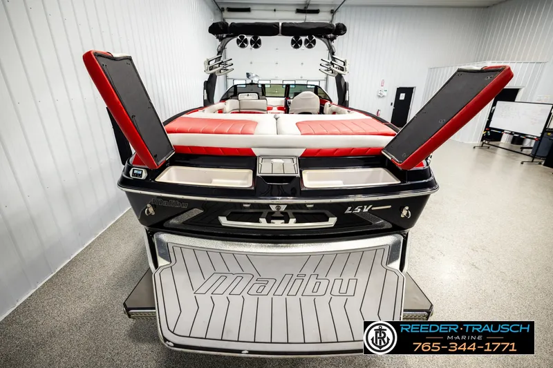 Slide: The Image of 2017 Malibu Wakesetter 25 LSV boat with red and white seating in a showroom. - 55