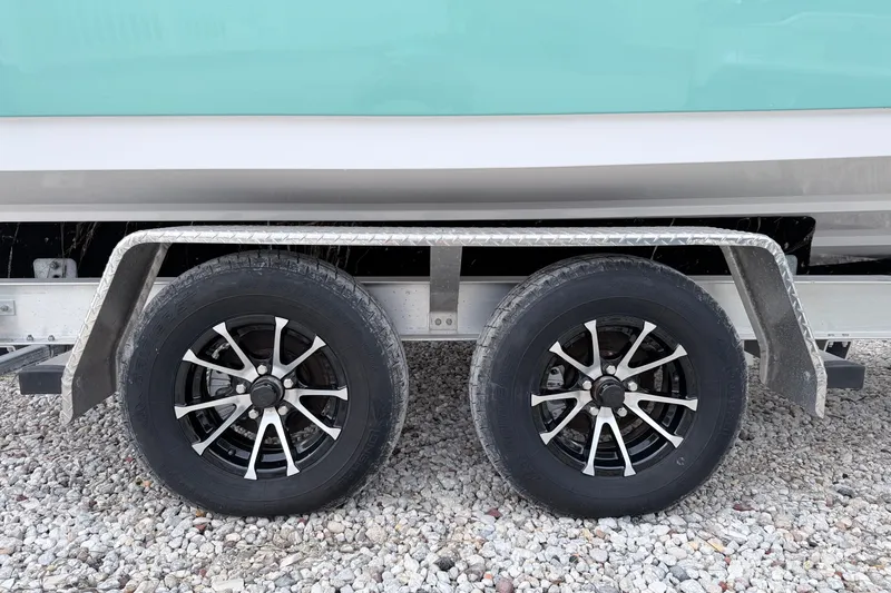 Slide: The Image of Trailer wheels of 2024 Sportsman Open 232 Center Console on gravel surface. - 5