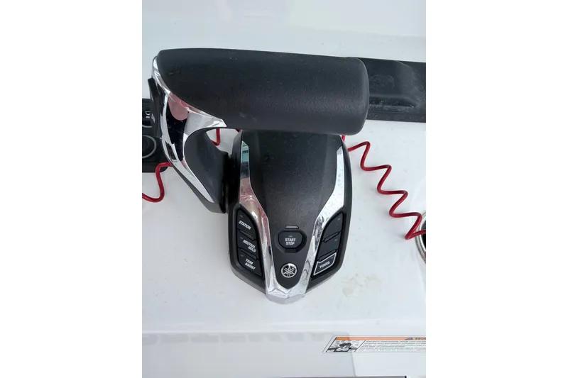 Slide: The Image of Throttle control of 2024 Sportsman Open 232 Center Console boat with red safety cord. - 15