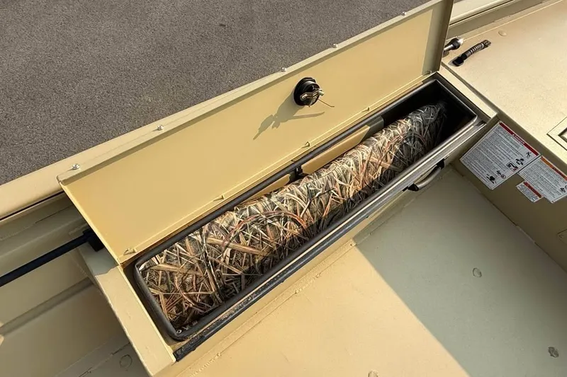 Slide: The Image of Storage compartment of 2026 Crestliner 1860 Retriever Deluxe boat with camouflage gear inside. - 7