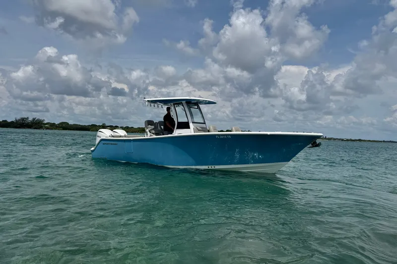 Slide: The Image of 2024 Sportsman Heritage 261 Center Console boat cruising on clear blue water under cloudy skies. - 10