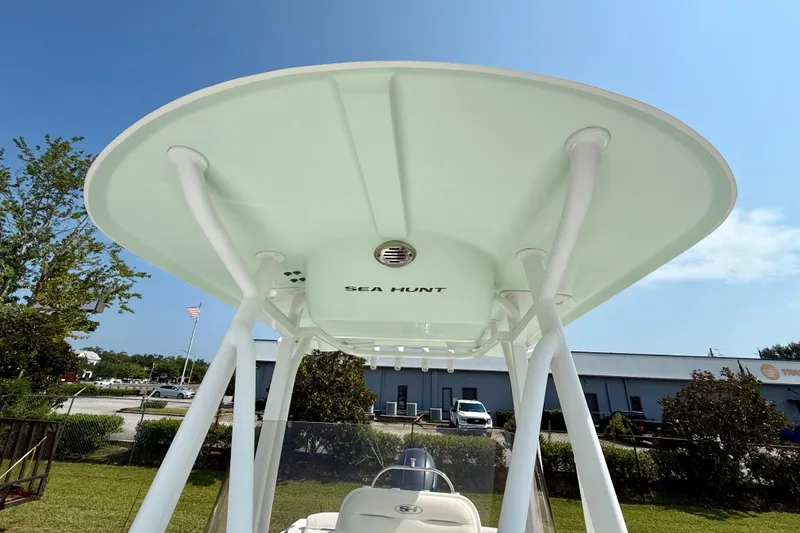 Slide: The Image of 2016 Sea Hunt Ultra 211 boat with T-top, parked outdoors under clear sky. - 12