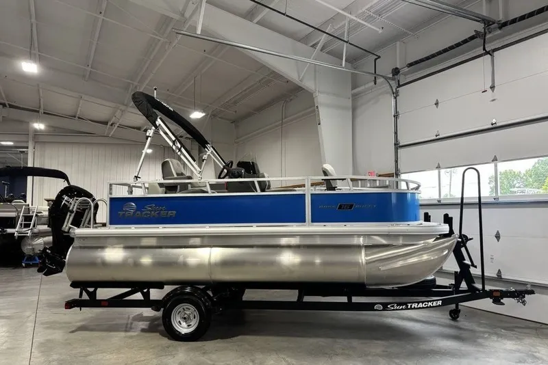 The Image of 2027 Sun Tracker Bass Buggy 16 XL Select pontoon boat in a showroom. - 2