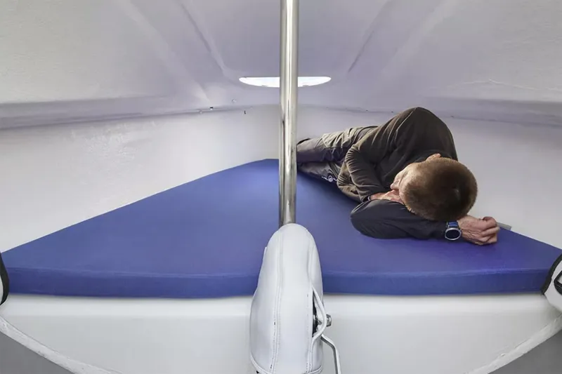 Slide: The Image of Manufacturer Provided Image: 2026 Beneteau First 18 SE cabin interior with person resting on blue mattress. - 4