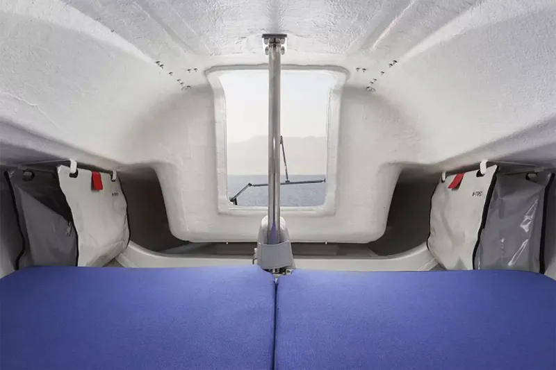 Slide: The Image of Manufacturer Provided Image: Interior cabin of 2026 Beneteau First 18 SE sailboat, featuring blue cushions and storage. - 3