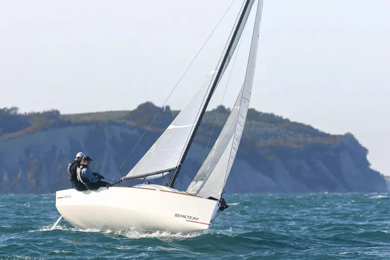 Slide: The Image of Manufacturer Provided Image: 2026 Beneteau First 18 SE sailboat navigating coastal waters with cliffs in the background. - 1