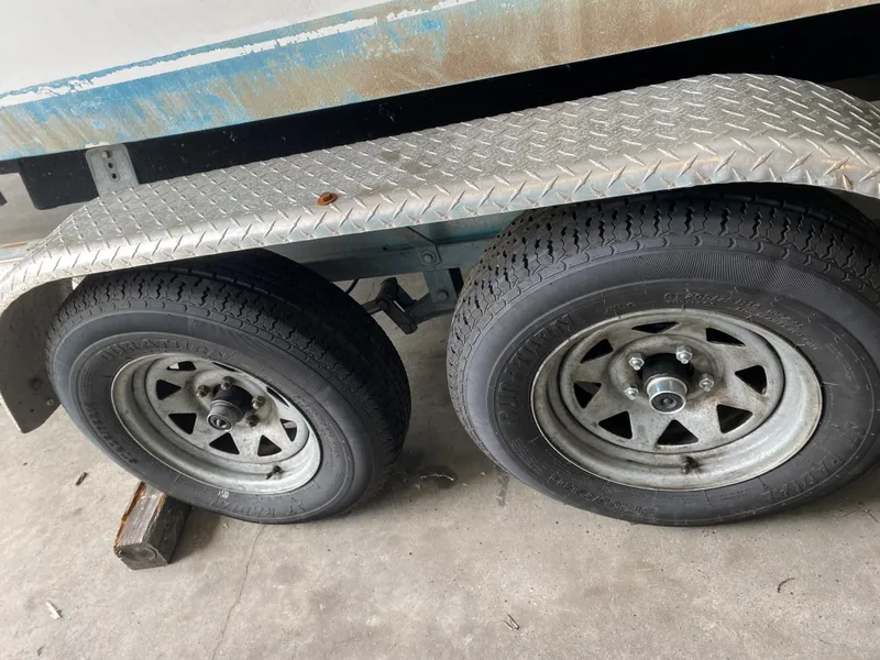Slide: The Image of Close-up of two trailer wheels with metal fenders supporting a boat trailer. - 23