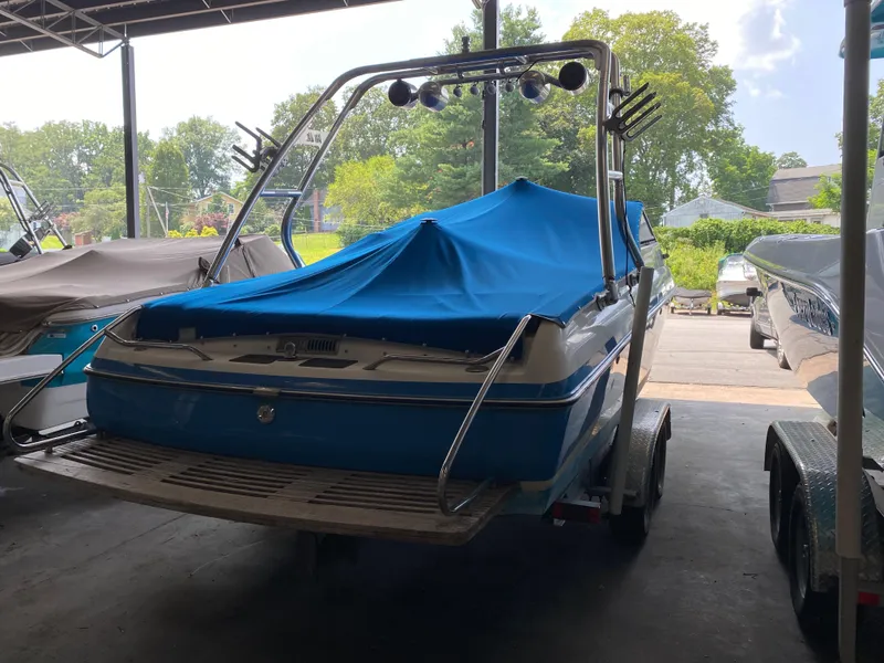 Slide: The Image of A 1990 MasterCraft Maristar 240 is parked in a covered area. It has a blue cover. - 3