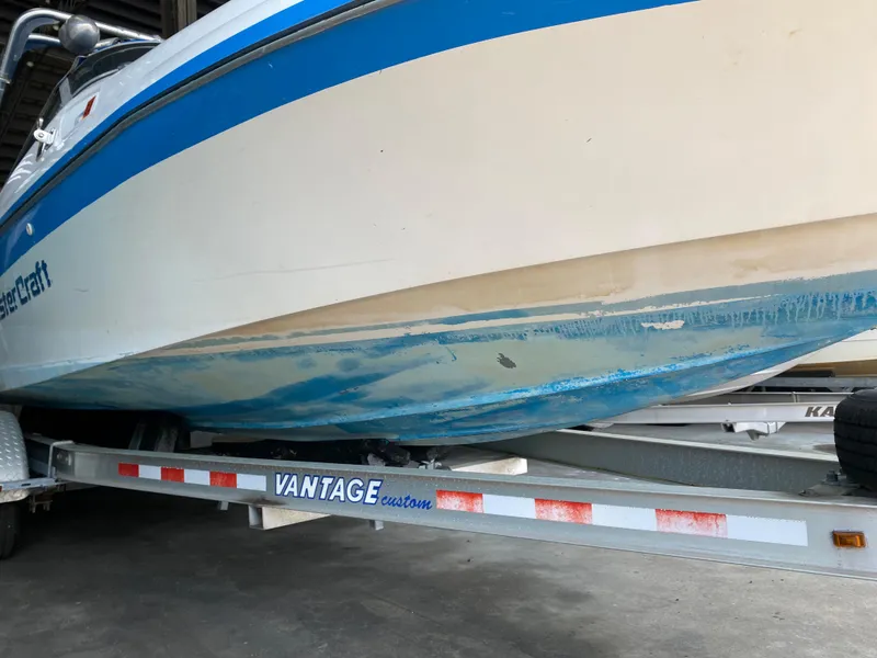 Slide: The Image of A 1990 MasterCraft Maristar 240 on a trailer. The underside shows signs of wear. - 2