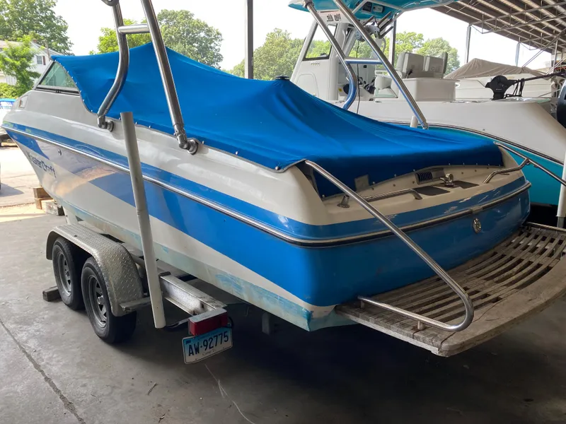Slide: The Image of A 1990 MasterCraft Maristar 240 with a blue cover on a trailer in a warehouse. - 4