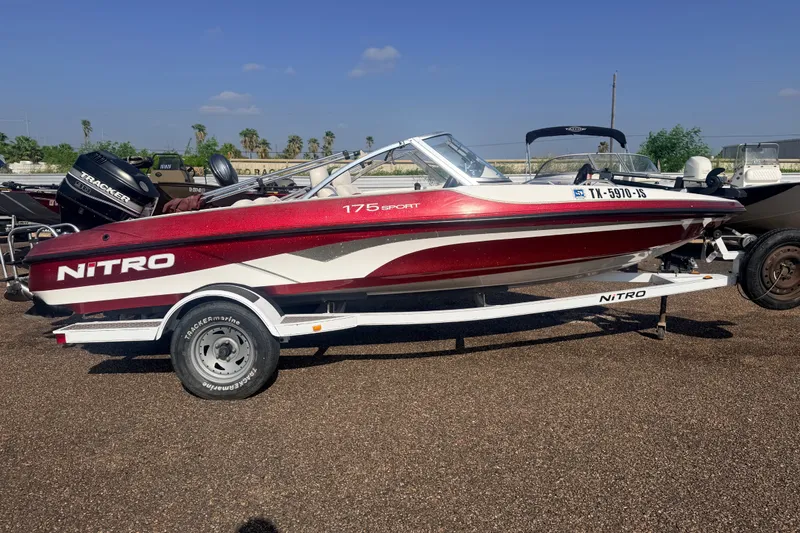 The Image of 2002 Nitro 175 Sport boat on trailer, red and white design, parked outdoors. - 2