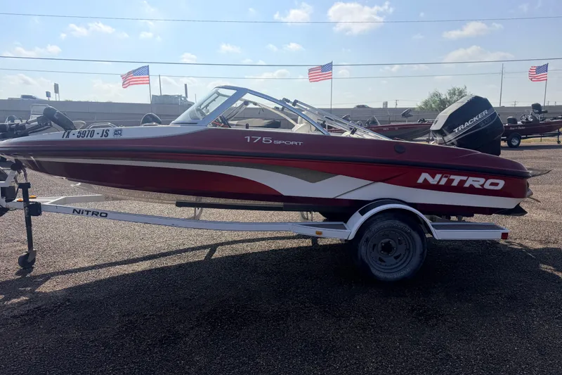 Slide: The Image of 2002 Nitro 175 Sport boat on trailer, parked outdoors with American flags in background. - 7