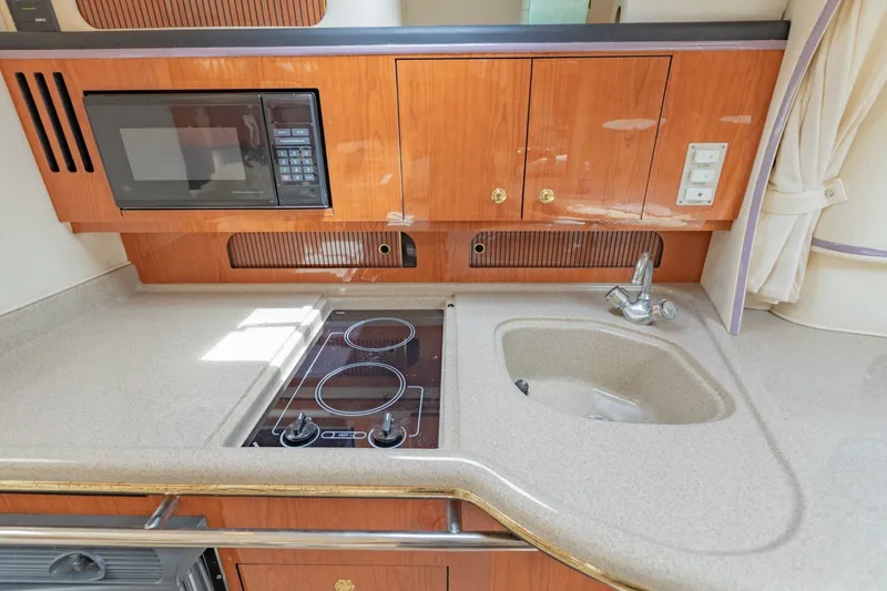 Slide: The Image of 2001 Sea Ray Sundancer 310 galley with microwave, stove, sink, and wooden cabinetry. - 26