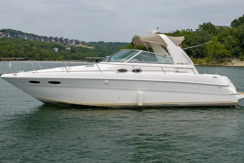 The Image of 2001 Sea Ray Sundancer 310 yacht on a serene lake with lush green shoreline. - 0