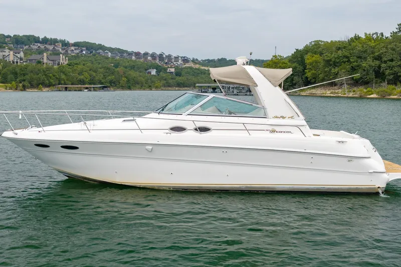 Slide: The Image of 2001 Sea Ray Sundancer 310 yacht on a serene lake with lush green shoreline. - 1