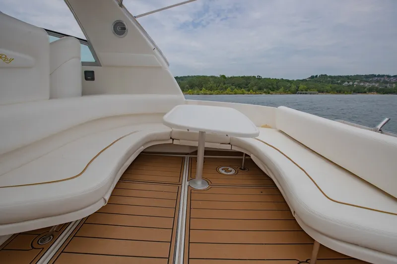 Slide: The Image of 2001 Sea Ray Sundancer 310 boat interior with white seating and table on a lake. - 9