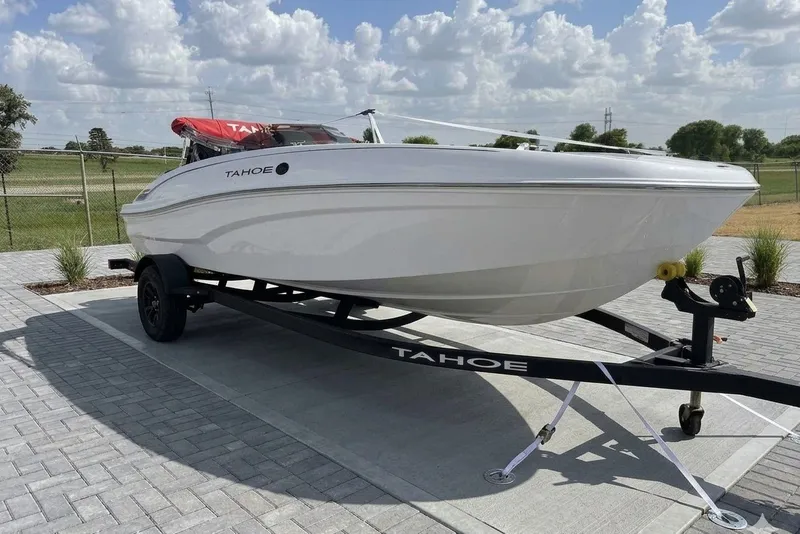 Slide: The Image of 2027 Tahoe T18 boat on trailer, parked on paved surface under a cloudy sky. - 1