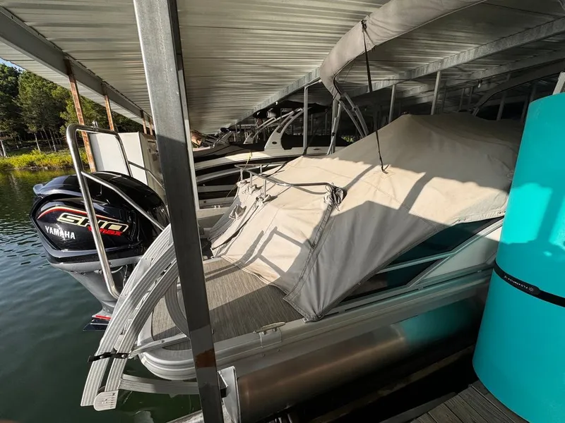 Slide: The Image of A 2023 Bennington 23SXSB is docked under a covered area. A Yamaha outboard motor is visible. - 14