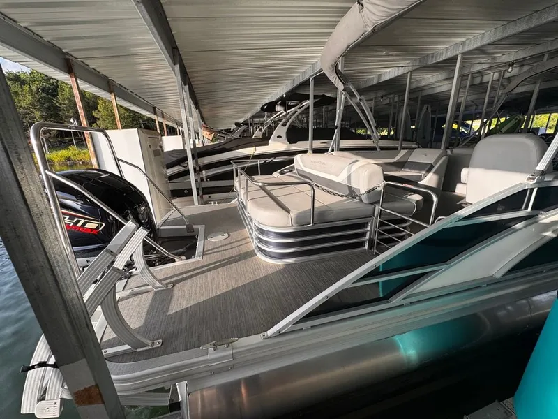 Slide: The Image of A modern Bennington pontoon boat, model 23SXSB, year 2023, docked under a covered area. - 8
