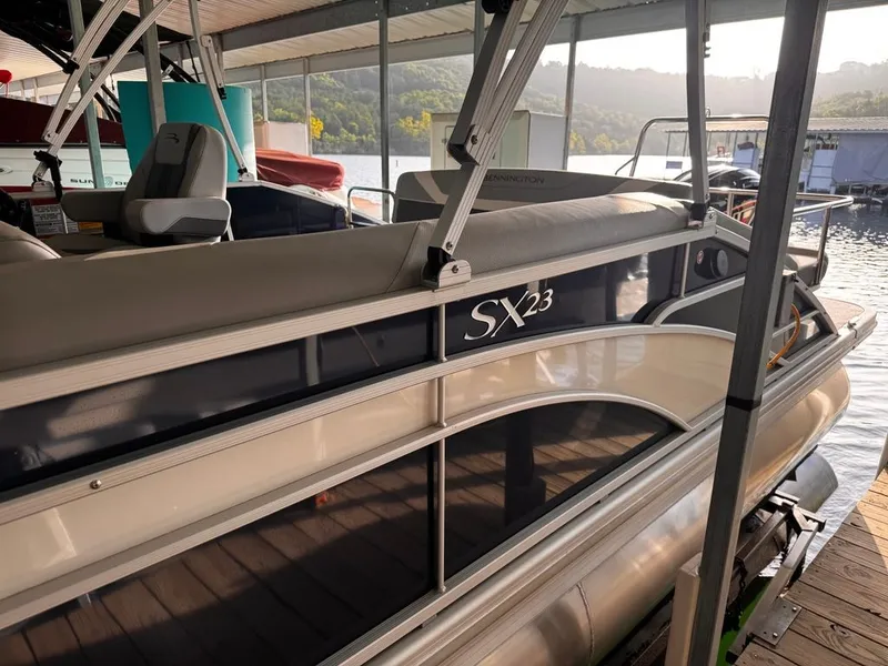 Slide: The Image of A 2023 Bennington 23SXSB pontoon boat docked. It features a sleek design. - 3