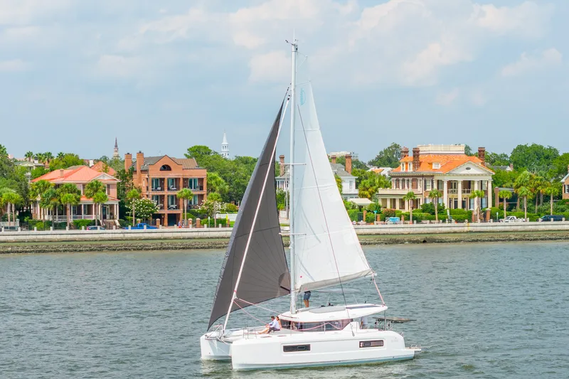 Slide: The Image of Sailing Lagoon 38 catamaran, 2026 model, near waterfront homes under a cloudy sky. - 5