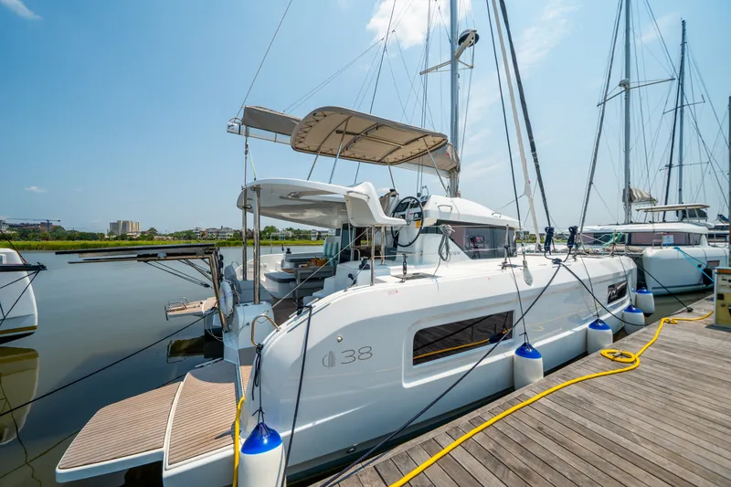 Slide: The Image of 2026 Lagoon 38 catamaran docked at marina under clear blue sky. - 7
