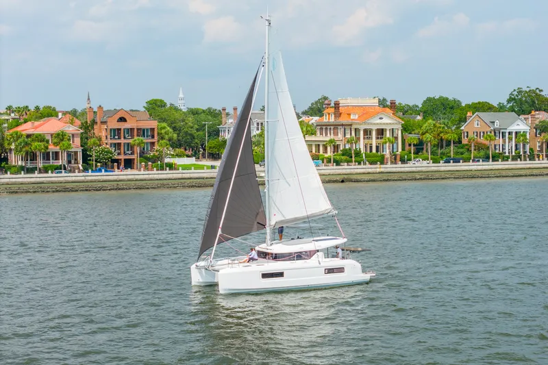 Slide: The Image of Sailing Lagoon 38 catamaran, 2026 model, near waterfront homes on a sunny day. - 3
