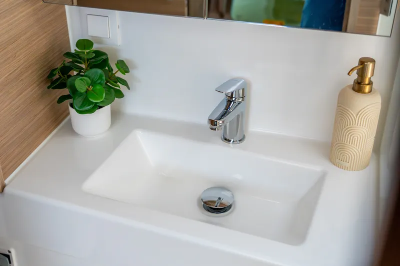 Slide: The Image of Modern bathroom sink with chrome faucet, potted plant, and soap dispenser on Lagoon 38, 2026 model. - 78