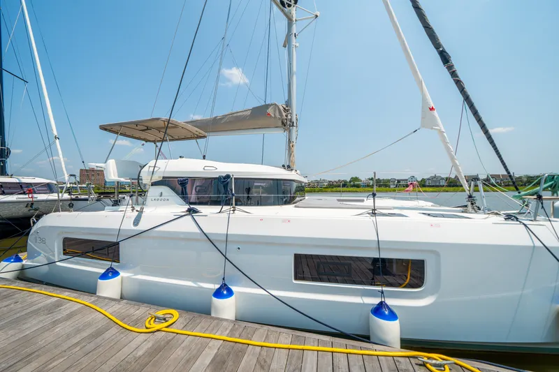 Slide: The Image of Modern 2026 Lagoon 38 catamaran docked at marina under clear blue sky. - 10