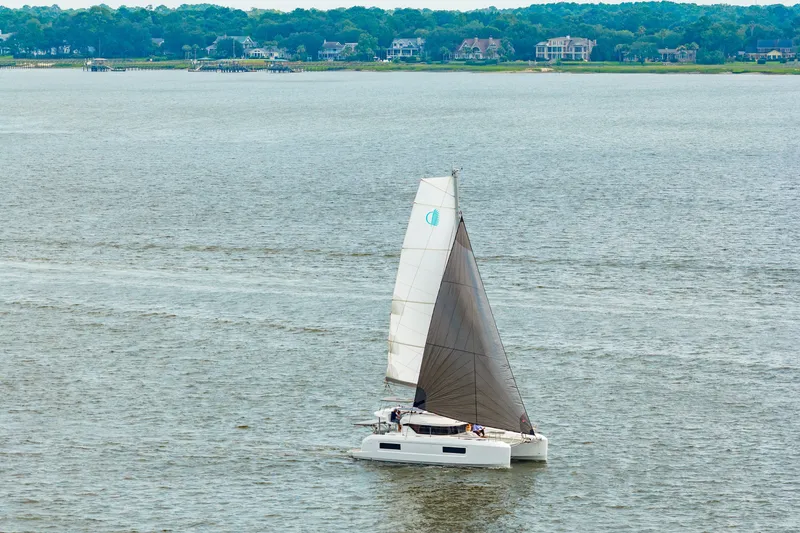 Slide: The Image of Sailing catamaran Lagoon 38, 2026 model, cruising on a serene lake with distant shoreline. - 4