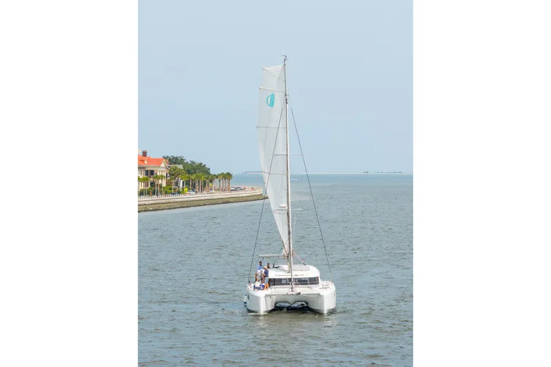 Slide: The Image of 2026 Lagoon 38 catamaran sailing near a coastal area with palm trees. - 126