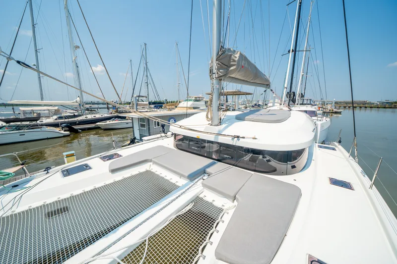 Slide: The Image of 2026 Lagoon 38 catamaran docked at marina, showcasing spacious deck and sleek design. - 14