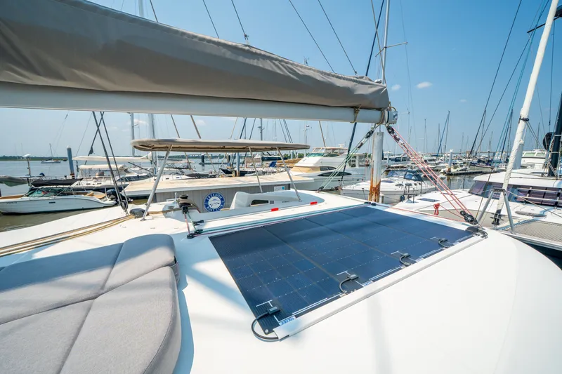 Slide: The Image of 2026 Lagoon 38 catamaran with solar panel, docked in a marina under clear blue skies. - 17