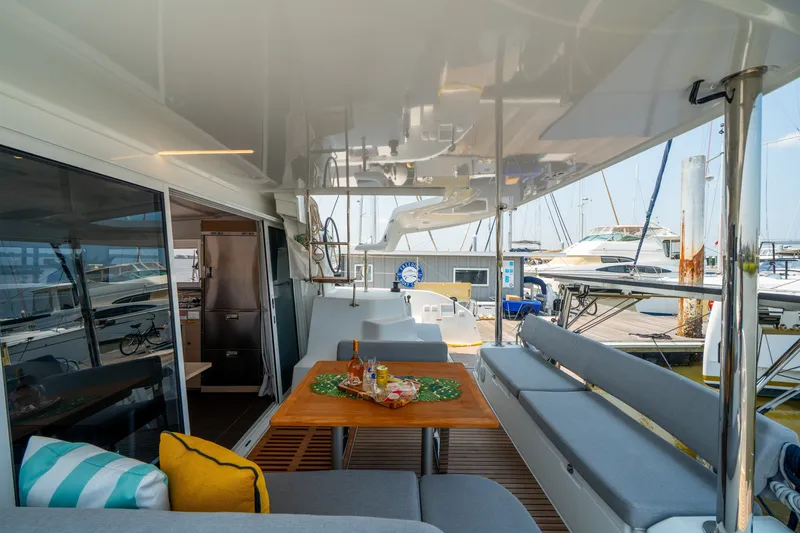 Slide: The Image of Modern Lagoon 38 catamaran interior, featuring a cozy seating area and dining table, docked at a marina. - 42