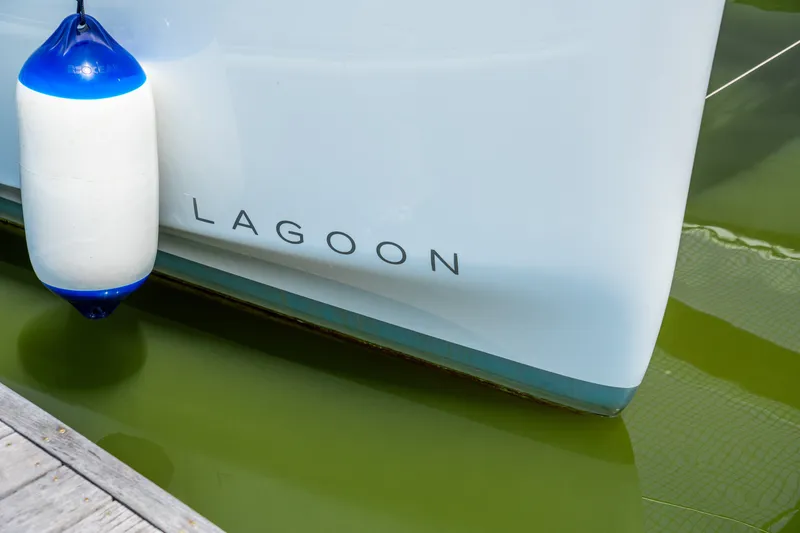 Slide: The Image of 2026 Lagoon 38 catamaran docked, featuring sleek hull design and protective fender. - 22