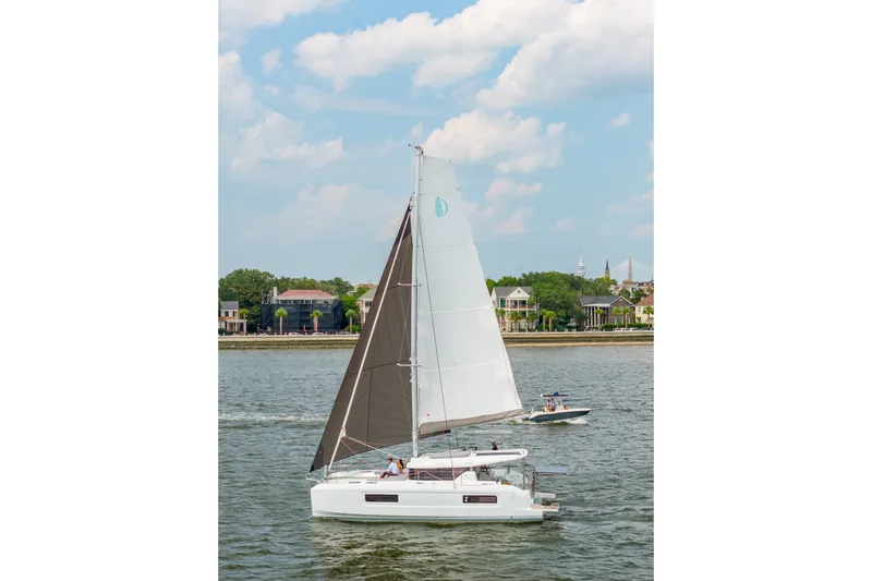 Slide: The Image of 2026 Lagoon 38 sailboat cruising on a calm river with scenic shoreline views. - 125