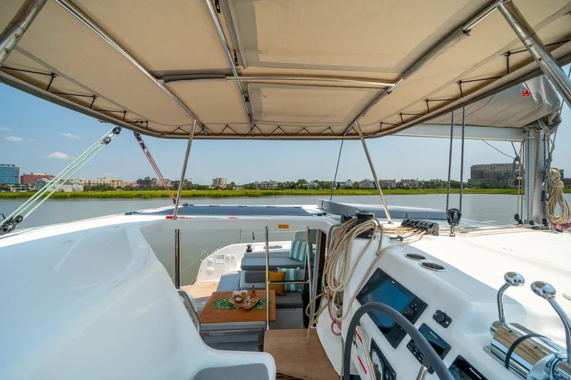 Slide: The Image of 2026 Lagoon 38 catamaran cockpit with canopy, overlooking serene waterfront and cityscape. - 37