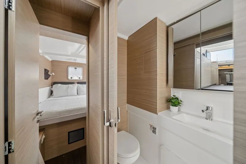 Slide: The Image of Modern bathroom and bedroom interior of 2026 Lagoon 38 yacht, featuring sleek wood finishes. - 72