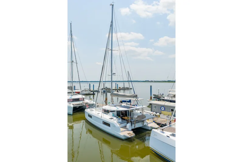 Slide: The Image of 2026 Lagoon 38 catamaran docked at a marina under a clear sky. - 89