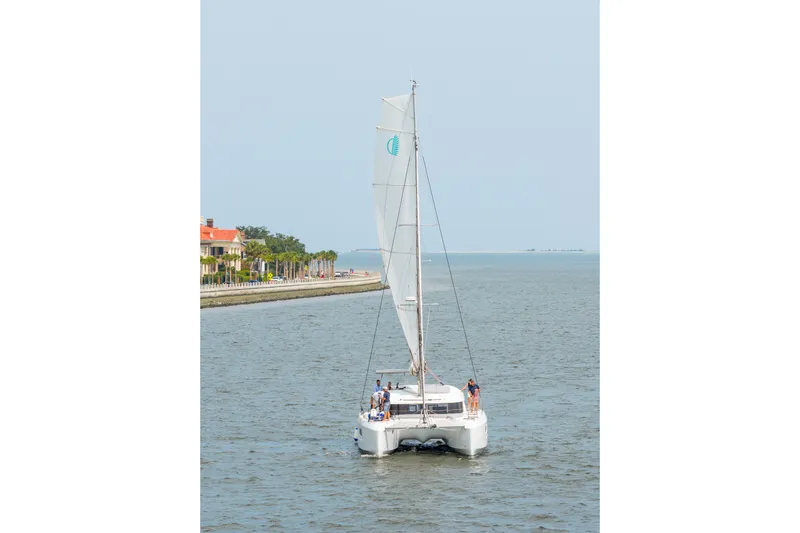 Slide: The Image of 2026 Lagoon 38 catamaran sailing near coastal area, featuring sleek design and spacious deck. - 106