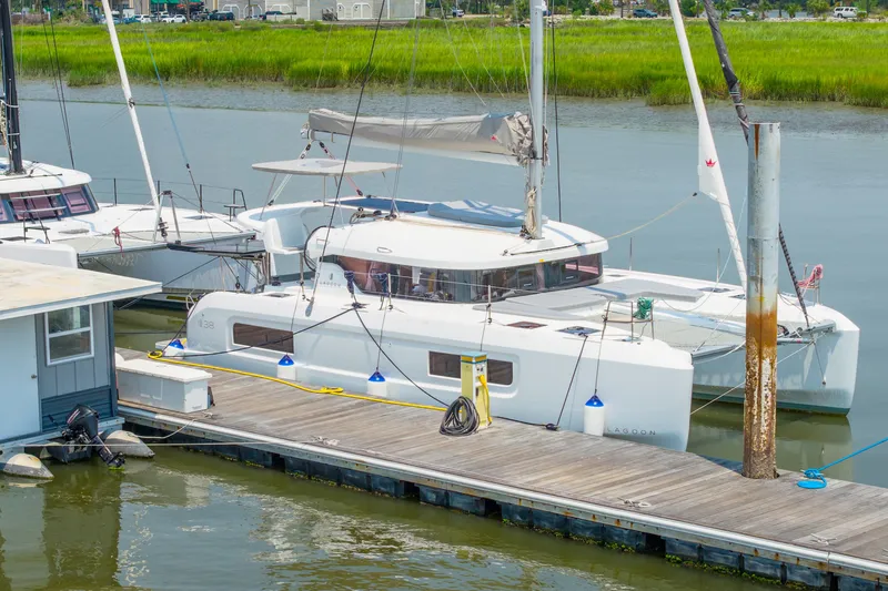 Slide: The Image of 2026 Lagoon 38 catamaran docked at marina, surrounded by calm water and greenery. - 83